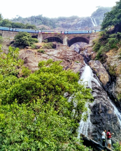 Bangalore to Goa train on an arched bridge with a waterfall beneath it