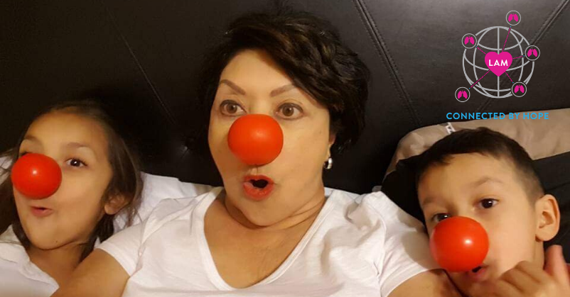 Maria, a woman, with two beautiful grandchildren, all wearing red noses; WWLAM 2020 logo in top right corner