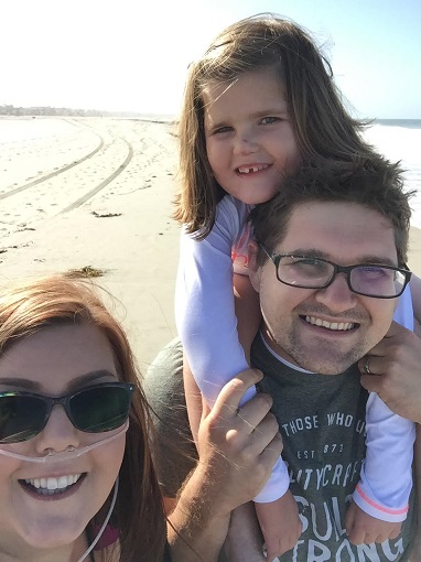 Woman, man, and child - a family - smiling at the beach