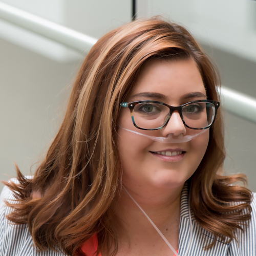 Meg, a woman with brown hair wearing glasses and an oxygen hose