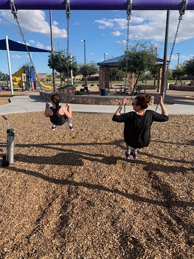 A woman and a child on a swingset, as seen from behind