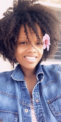 Najah, a woman, smiling with a pink flower in her ear