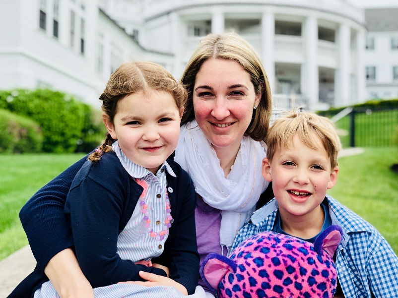 Steph sitting with her beautiful two children on a lawn in front of a white building