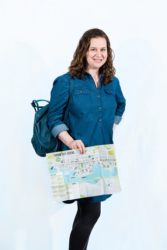 Sarah standing with a map and her backpack, featured in a new book about women with LAM