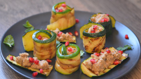 Black plate with zucchini wrapped and topped with walnut spread