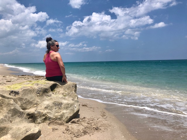 Sarah, a woman with LAM, sitting on the beach staring out at the ocean