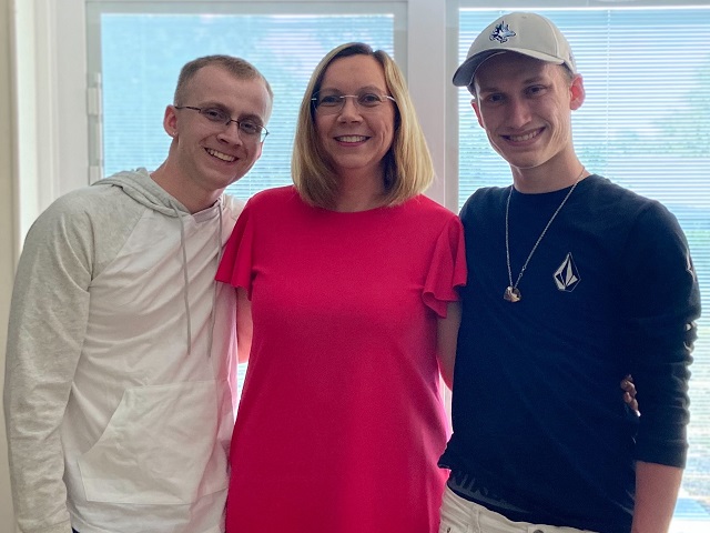 Susan - a woman with LAM - standing flanked by her two adult sons